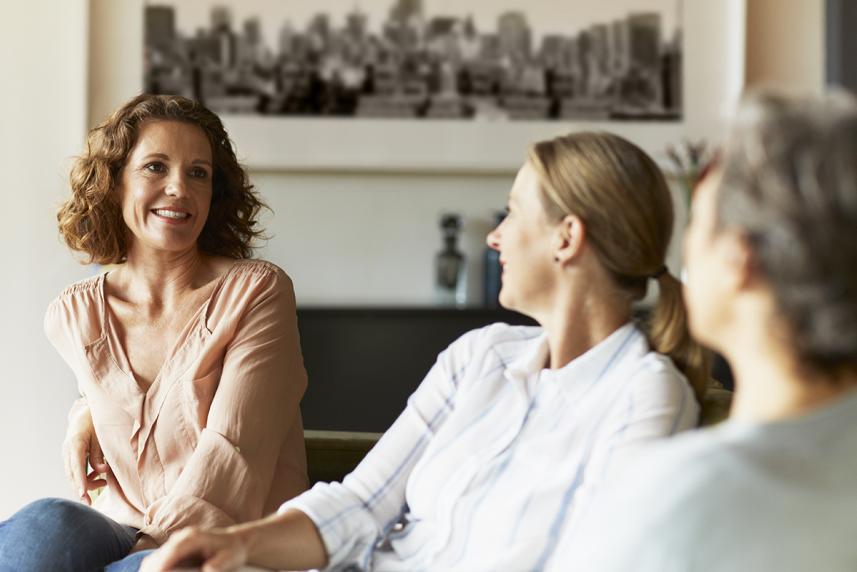 A group of women sitting on a couch looking at each other