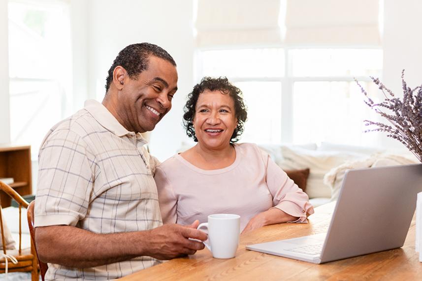 A smiling couple in front of a laptop